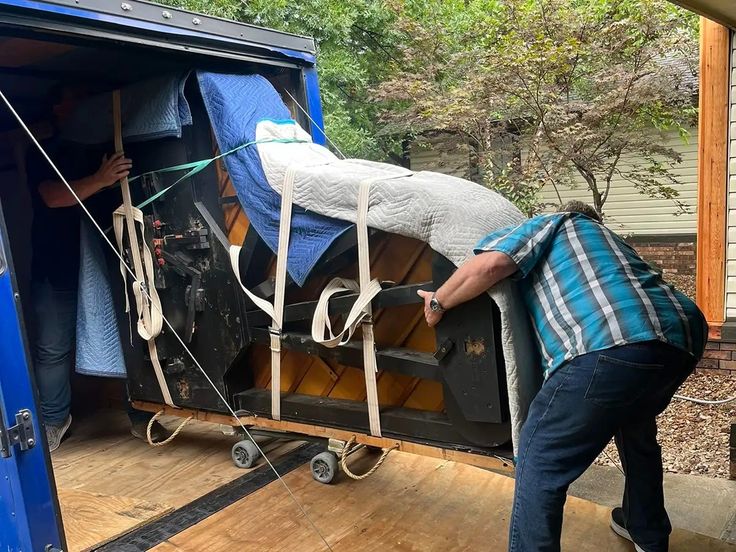 Piano secured with heavy-duty straps and padding on specialized moving equipment
