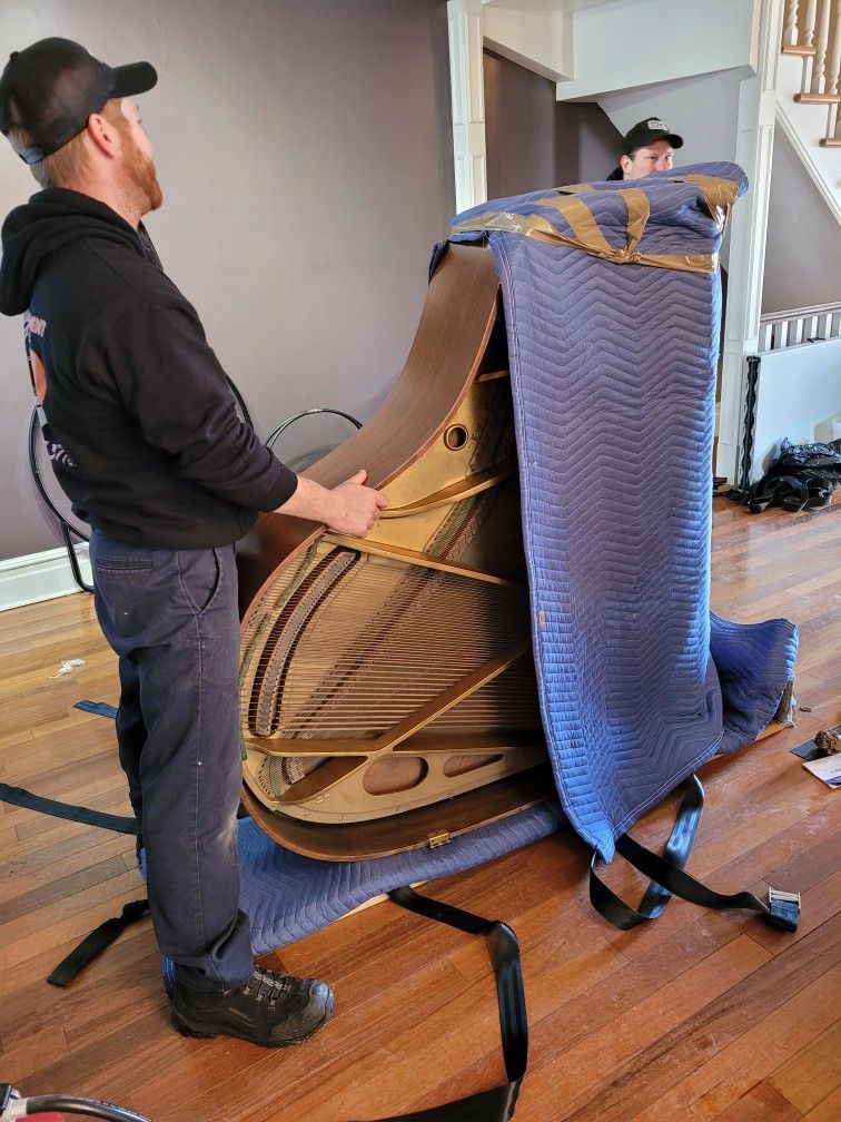 Exposed piano strings and soundboard being carefully wrapped and protected